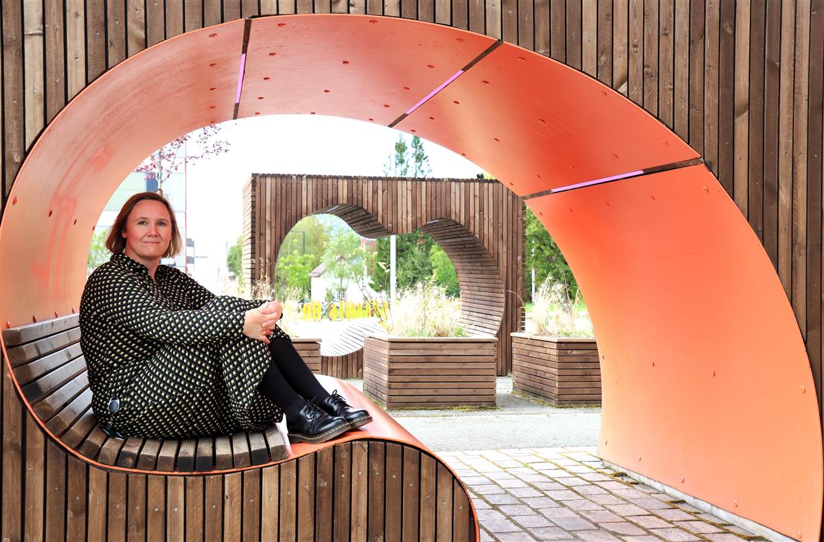 Kvinne som sitter på en innebygget benk inne i et slags ovalt rom.  - Klikk for stort bilde